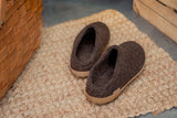 Pair of brown slippers on a textured surface next to a woven basket.