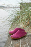 Pair of pink slippers on a wooden surface with grass in the background