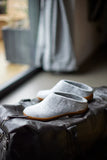 Pair of Grey felt slippers on a leather surface with a blurred background