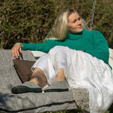 Woman in a teal sweater and white pants sitting outdoors wearing Glerups slippers